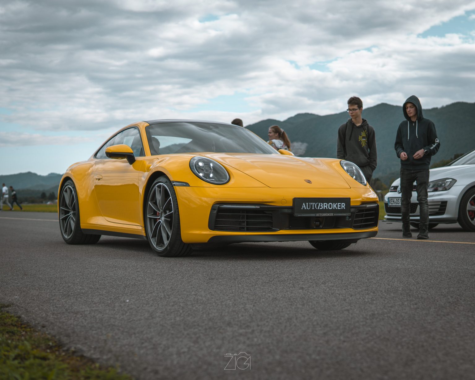 Rumen Porsche 911 na letališki stezi z gorami v ozadju